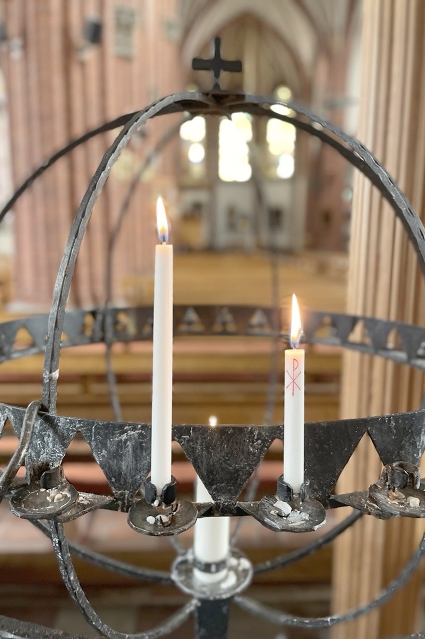 Tända ljus i en smidd ljuskrona framför koret i Uppsala domkyrka
